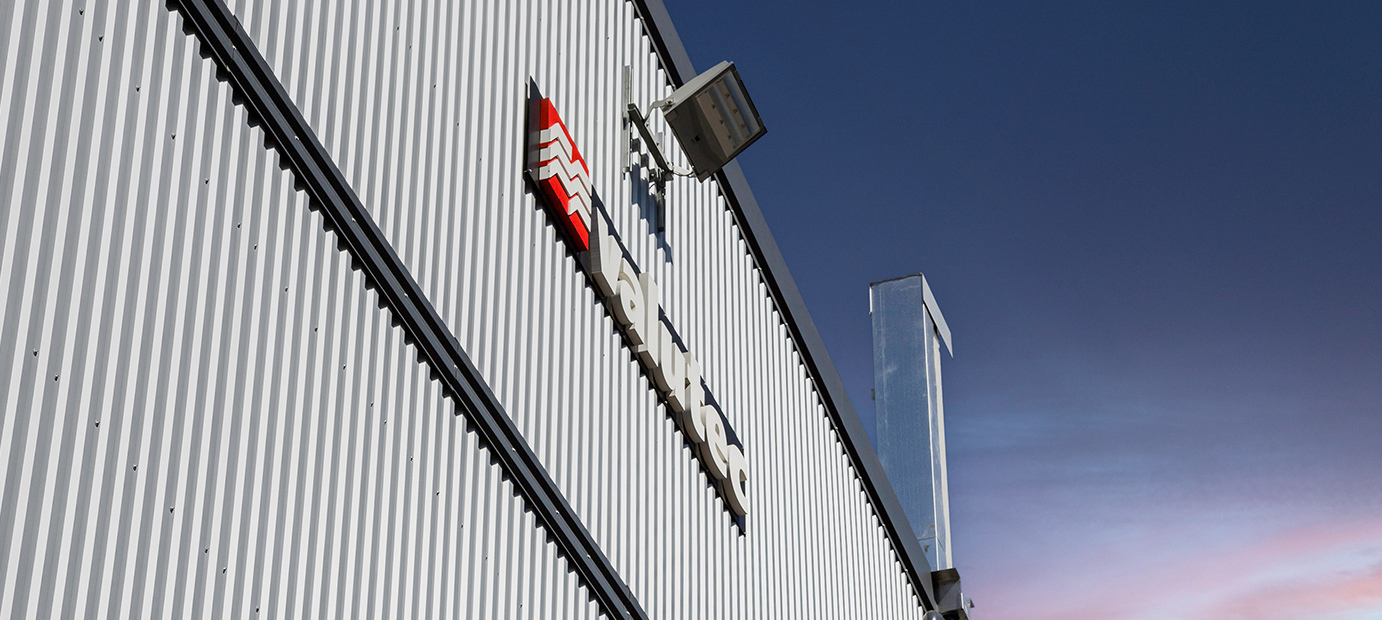 Valutec logotyp på fasad av plåtbyggnad mot blå himmel.