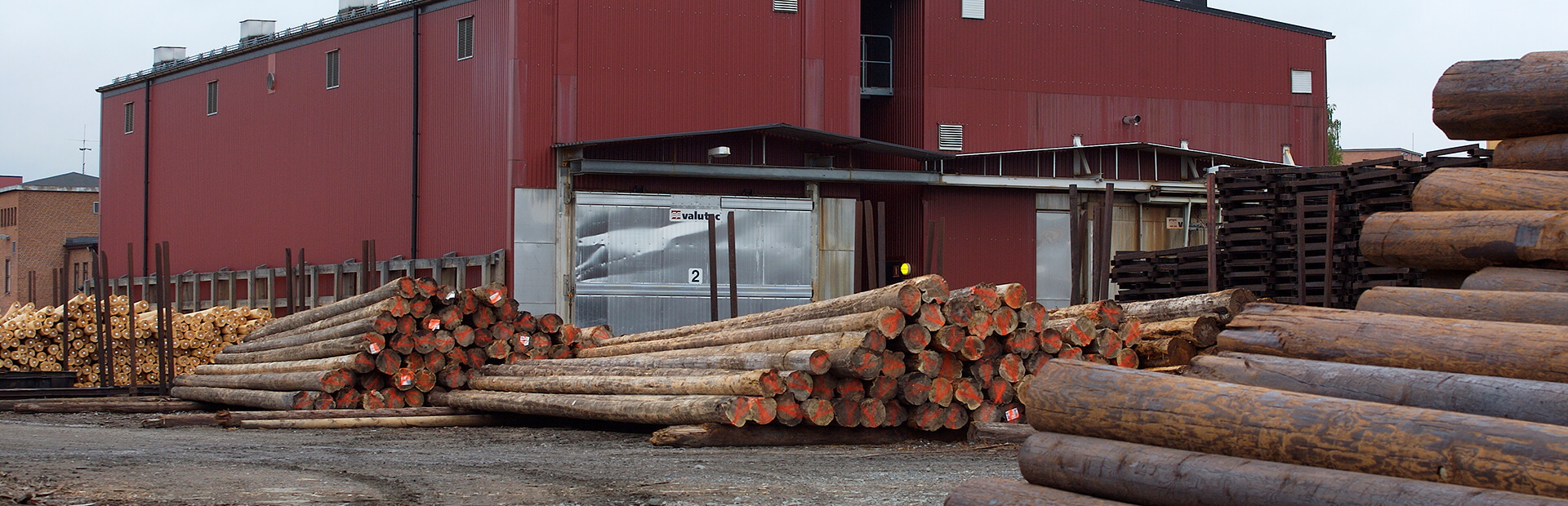 Truckmatad kammartork från Valutec med impregnerade stolpar upplagda framför byggnaden.