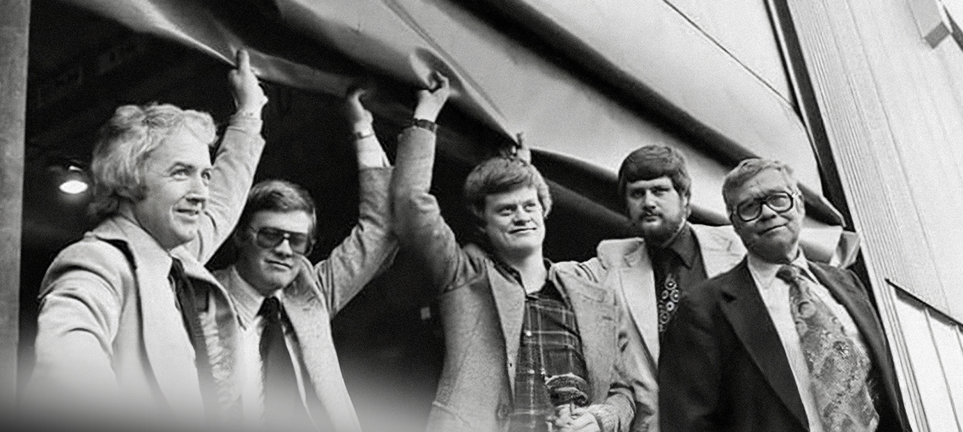 Tidigt svartvitt foto från Valutecs historias, bild av män i kostym vid port.