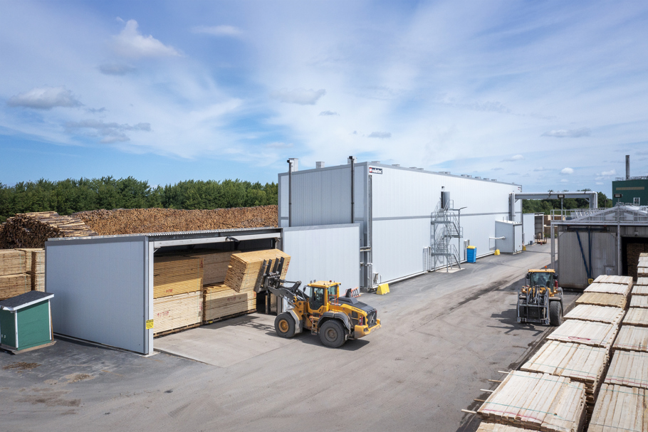 Kanaltork från Valutec med virkespaket och hjullastare utanför anläggningen.