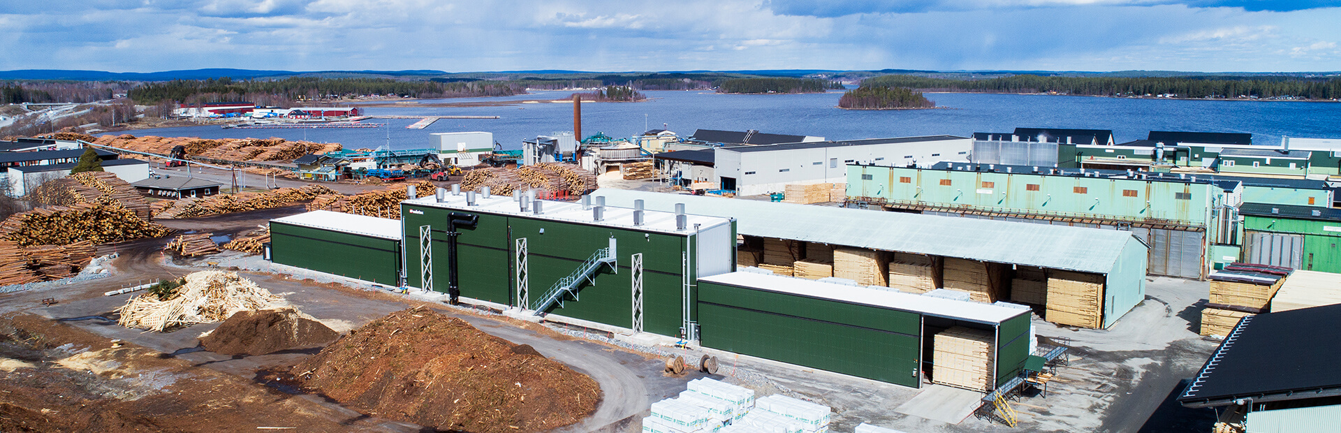 Valutec kanaltork TC i grönt, belägen vid sågverk med utsikt över vatten och omgivande skog.