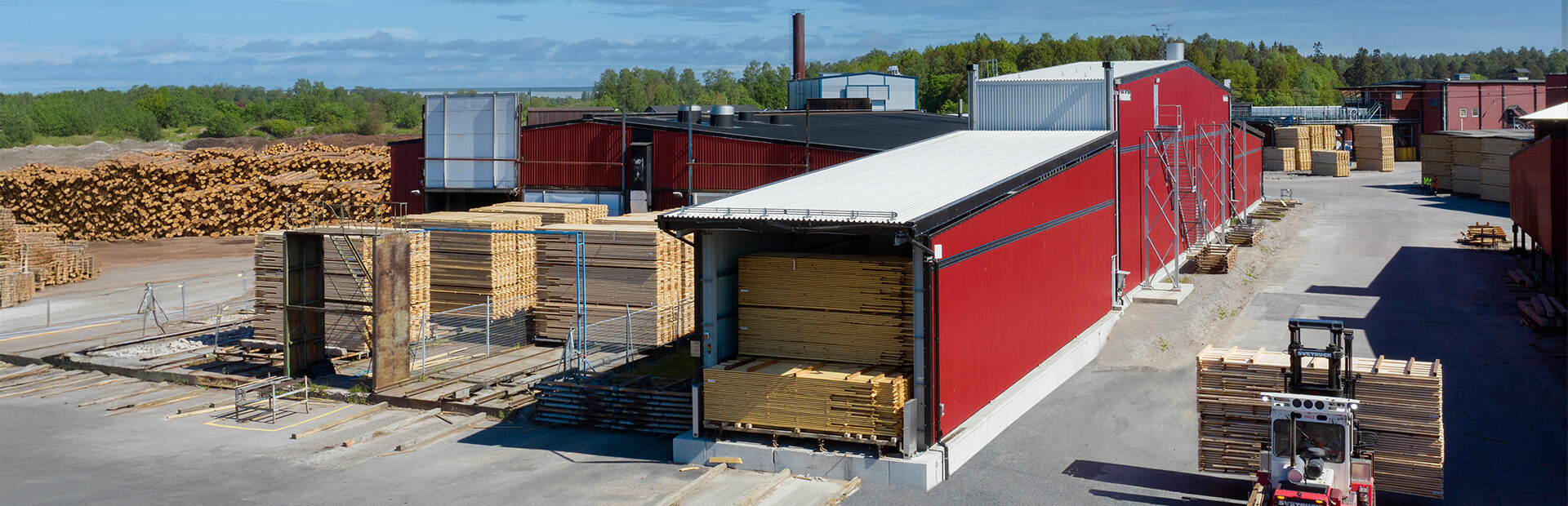 Truck lastar virkespaket framför Valutec 2-zonskanaltork