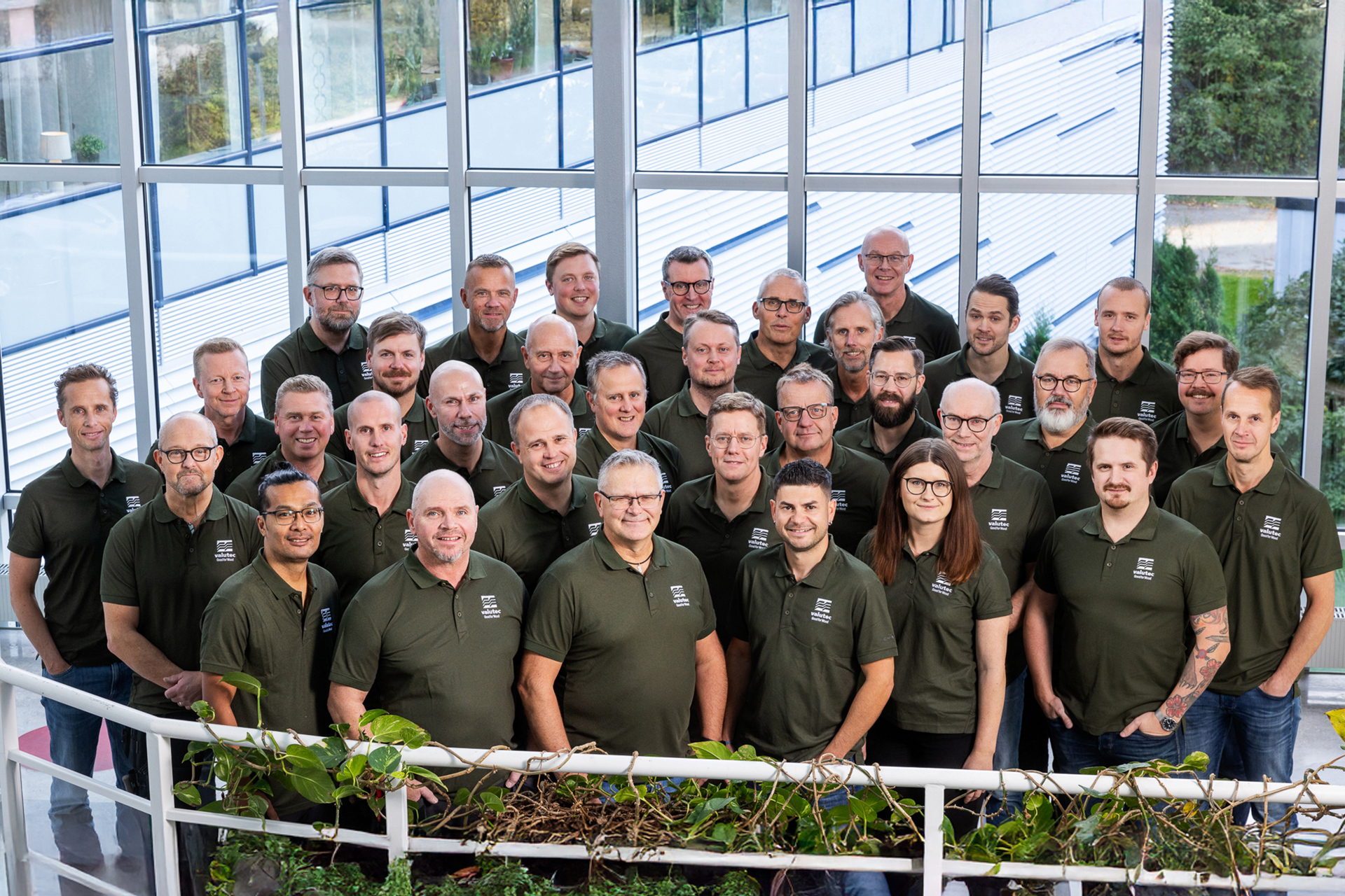 Gruppbild på Valutecs medarbetare i gröna skjortor, fotograferad inomhus.