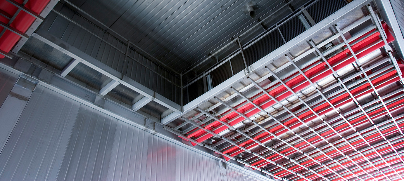 Invändig vy av Valutecs virkestork som visar tryckramens konstruktion med röda rör och metallgaller.