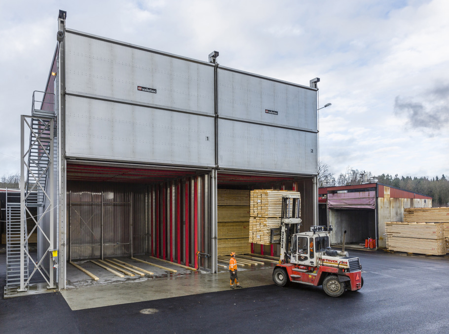 Hjullastare som lastar virke bredvid en arbetare.