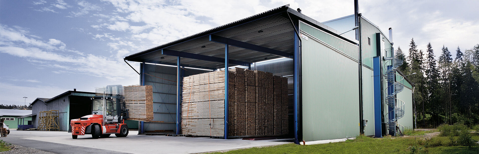 E-vagnsmatad kammartork fylld med virke, med röd truck som lastar virkespaket.